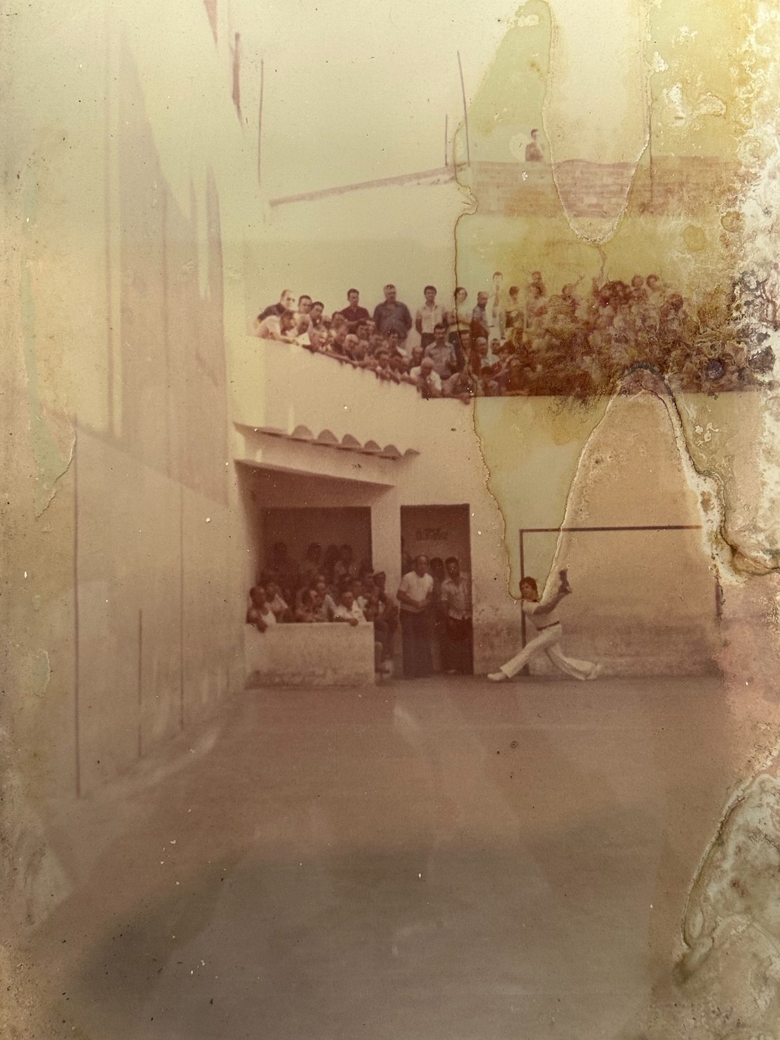 Foto antiga del trinquet: El Genovés colpejant la pilota, amb el públic dalt de la grada